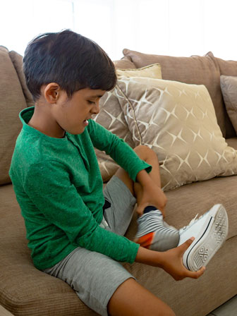 boy sitting on a couch removing his shoe